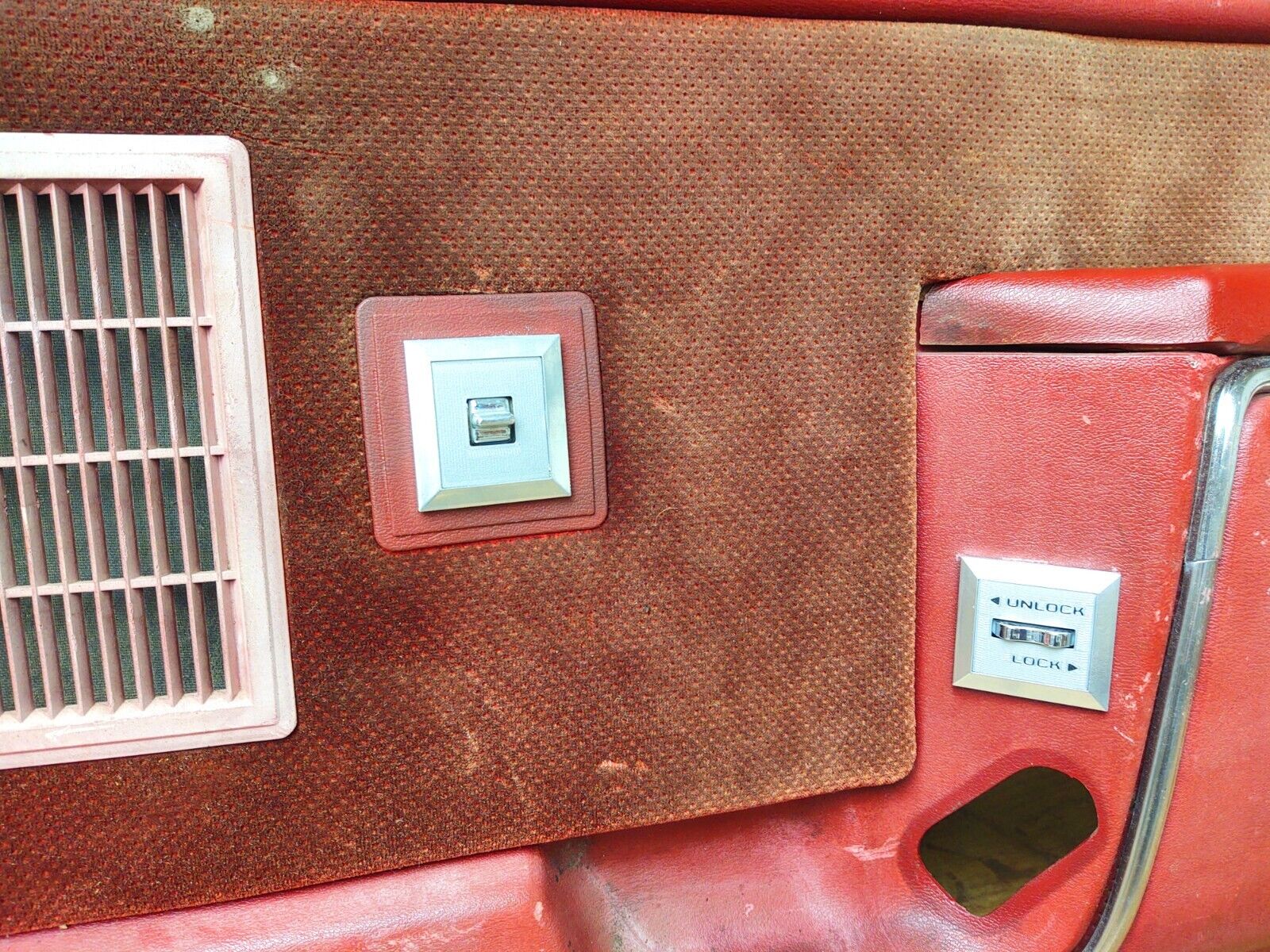 Reddish-brown power window switch bezel housing a silver switch, installed on the passenger side door panel of a 1980-1986 Ford F-Series truck or Bronco.