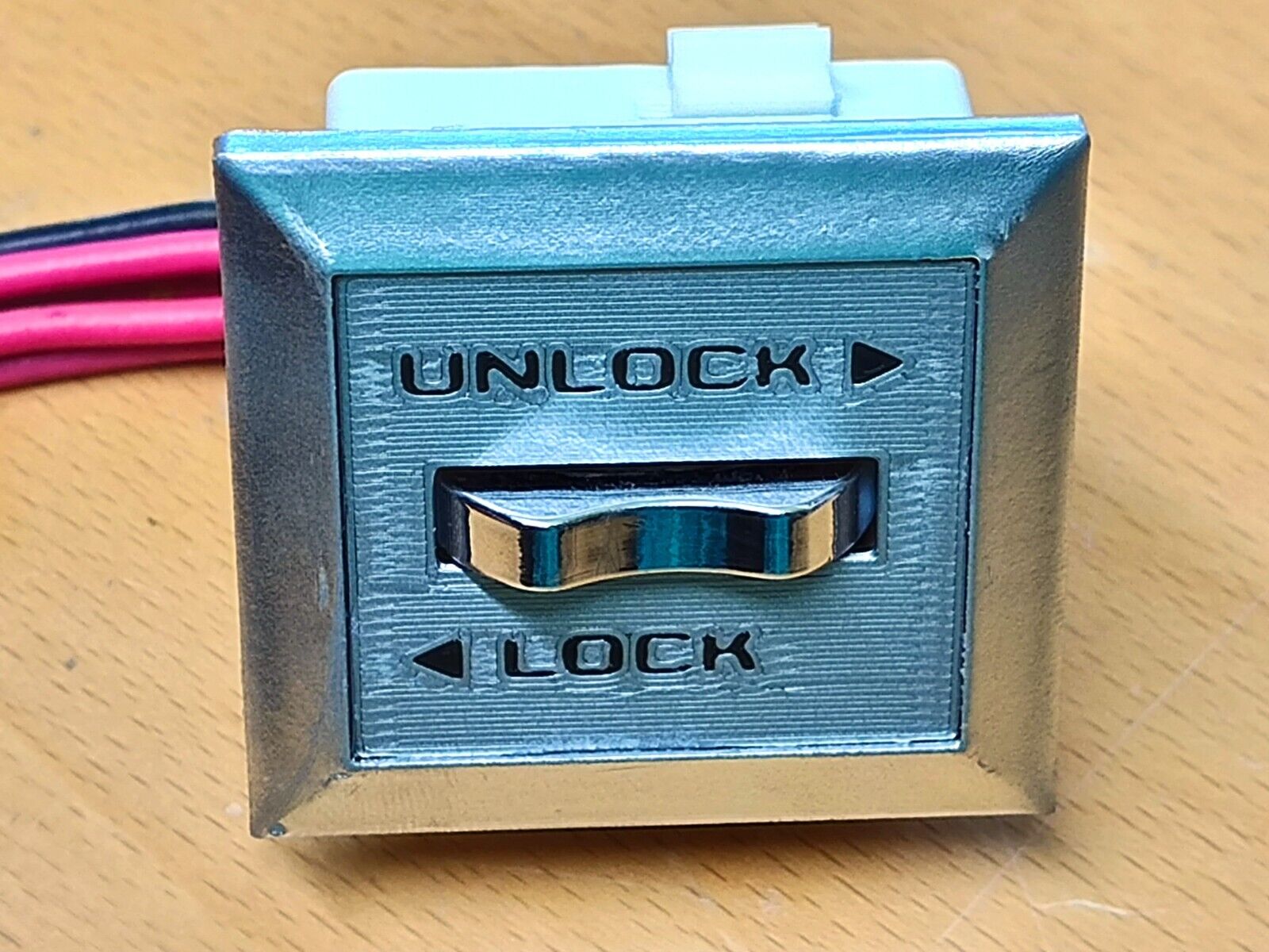Chrome power door lock switch bezel for 1980-1986 Ford F-150, F-250, F-350, and Bronco, featuring black 'UNLOCK' and 'LOCK' text with directional arrows and a center rocker switch.