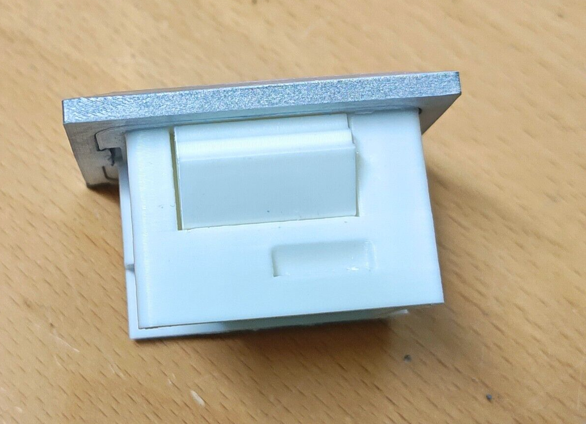 Rear view of a 1980-1986 Ford passenger side power window bezel (PW80R) showing the textured silver trim and white plastic mounting housing with clips.