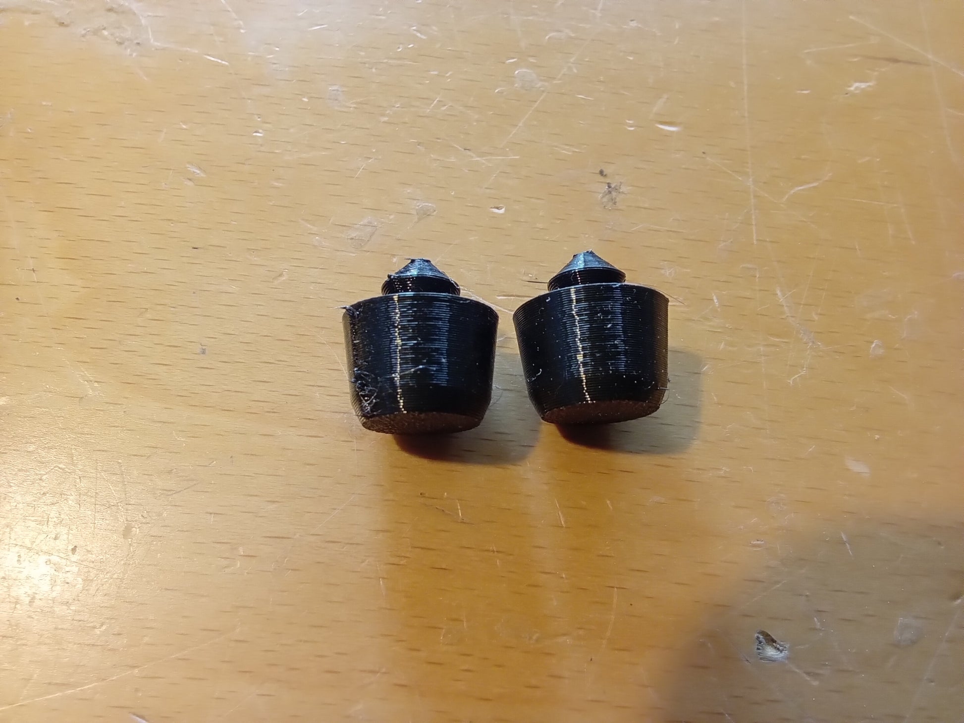 Two black rubber lid bumpers on a wooden surface, designed for Ford center consoles by Blue Truck Parts.