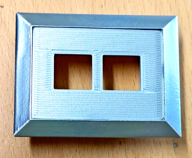 Grey left power window bezel for 1980-1986 Ford F-150, F-250, F-350, and Bronco. Features a textured rectangular face with two square switch cutouts and a smooth silver-grey border.