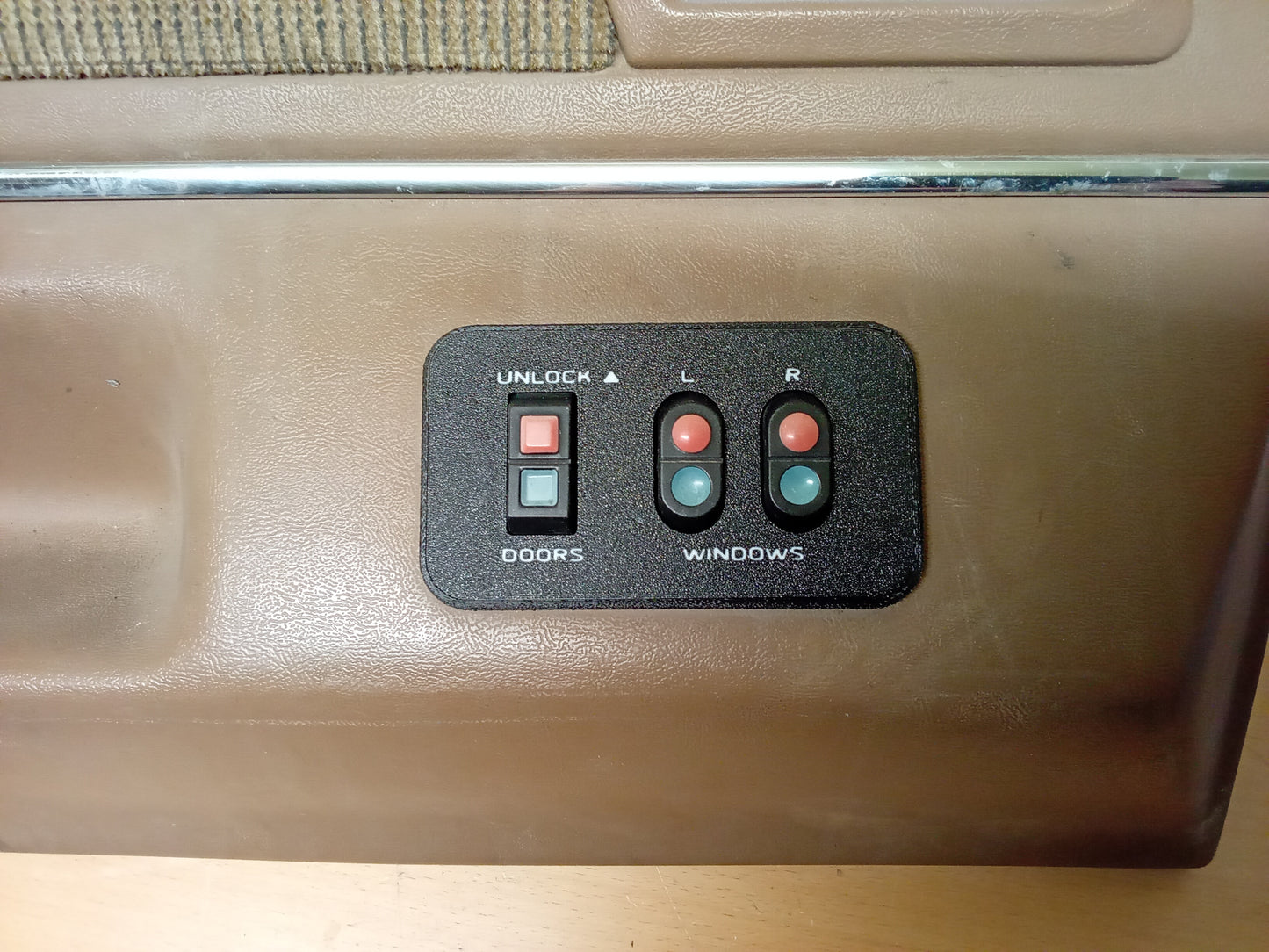 Black power window and lock bezel for Ford vehicles, featuring buttons for unlocking and controlling left and right windows.