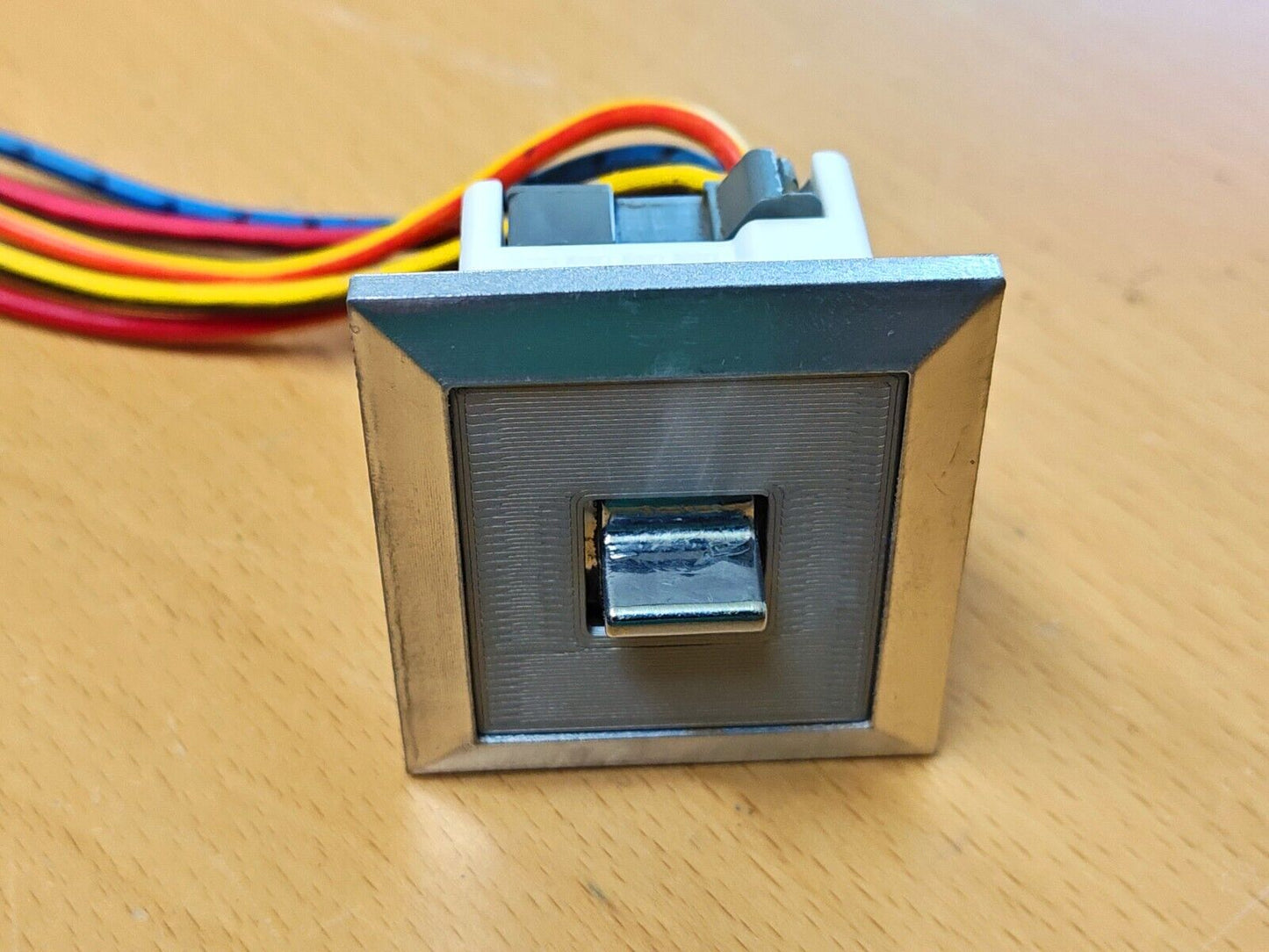 Right power window switch bezel with chrome trim, textured grey face, and chrome toggle switch for 1980-1986 Ford F150, F250, F350, and Bronco, with connected wiring harness.