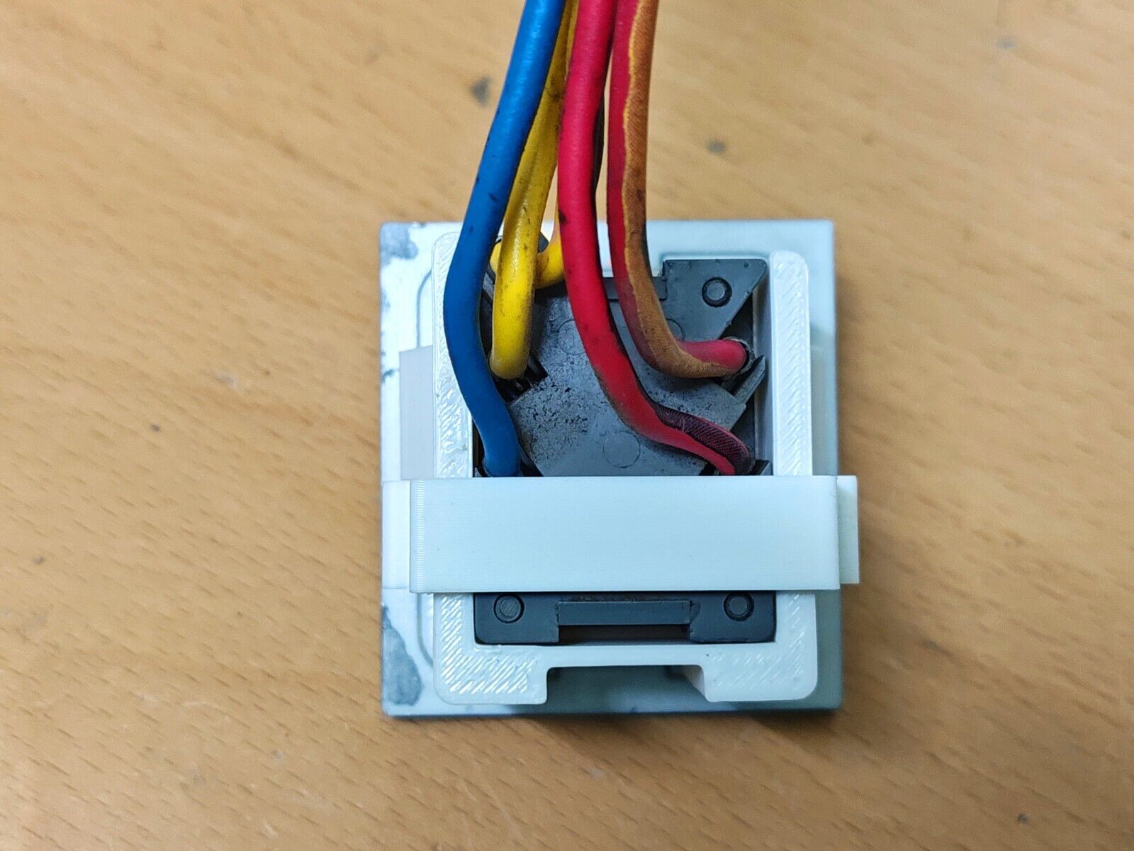 Rear view of the 1980-1986 Ford passenger power window bezel PW80R, showing the OEM switch connector and colorful wiring secured in place by the included white retainer clip.