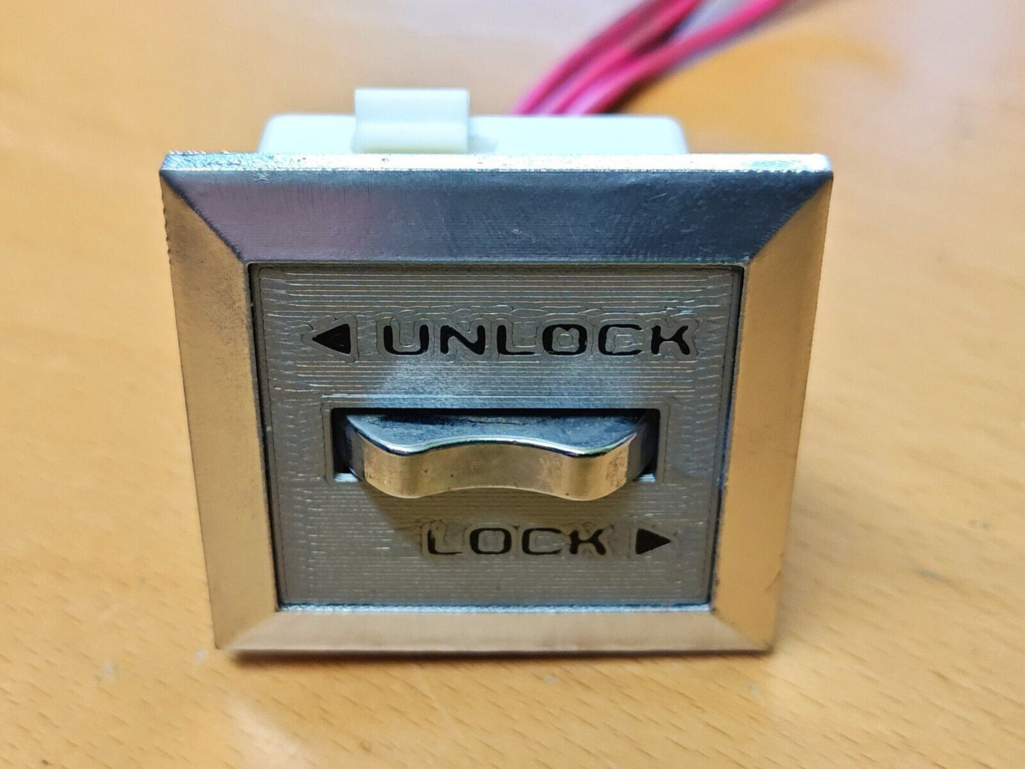 Passenger side power door lock switch for 1980-1986 Ford trucks and Bronco, featuring a chrome bezel, textured silver faceplate, and black LOCK and UNLOCK text with arrows.
