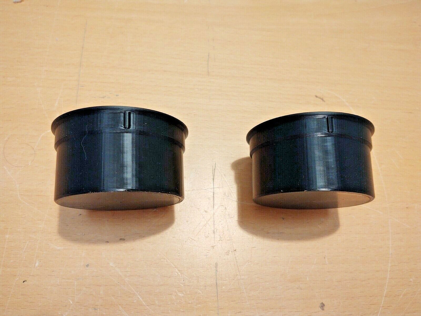 A pair of black polymer cup holder inserts for the center console of 1992-1996 Ford F-150, F-250, F-350, and Bronco vehicles.