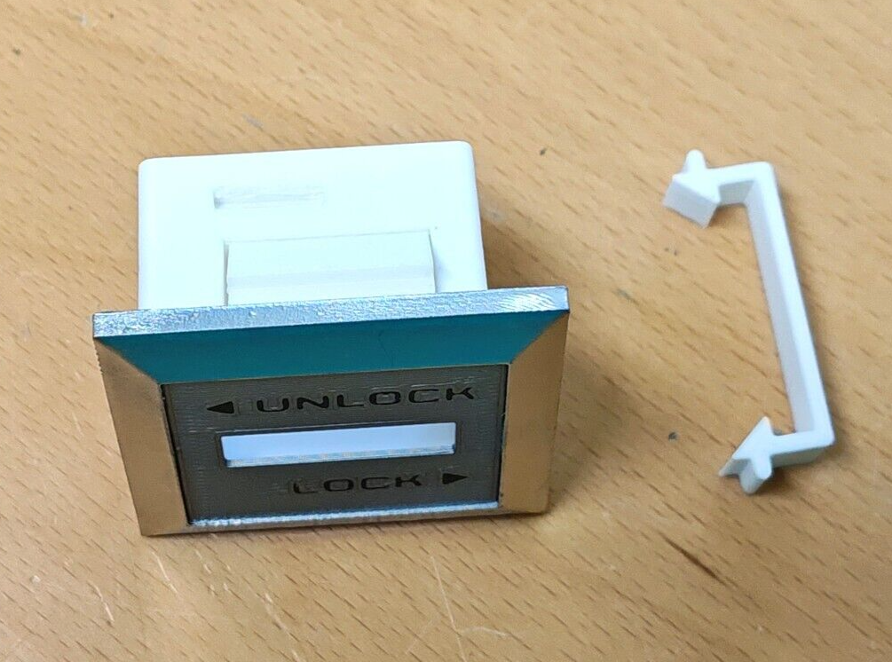 Right side power door lock bezel with chrome trim, 'UNLOCK' and 'LOCK' markings, and a white plastic housing, pictured next to a separate white retainer clip for 1980-1986 Ford F-Series trucks and Bronco.