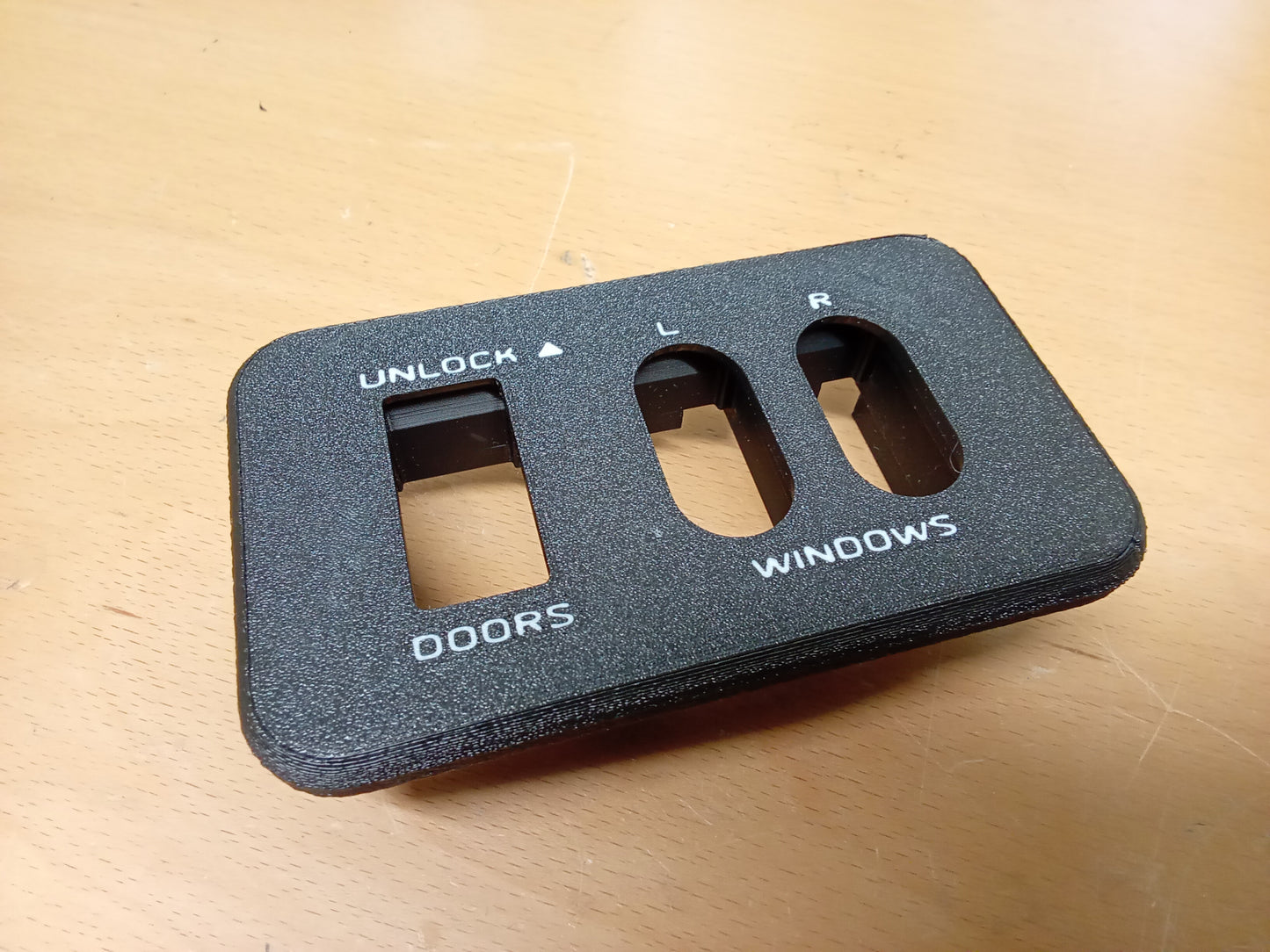 Black power window and door lock bezel for 1987-1991 Ford F-Series and Bronco, featuring labeled slots for switches.