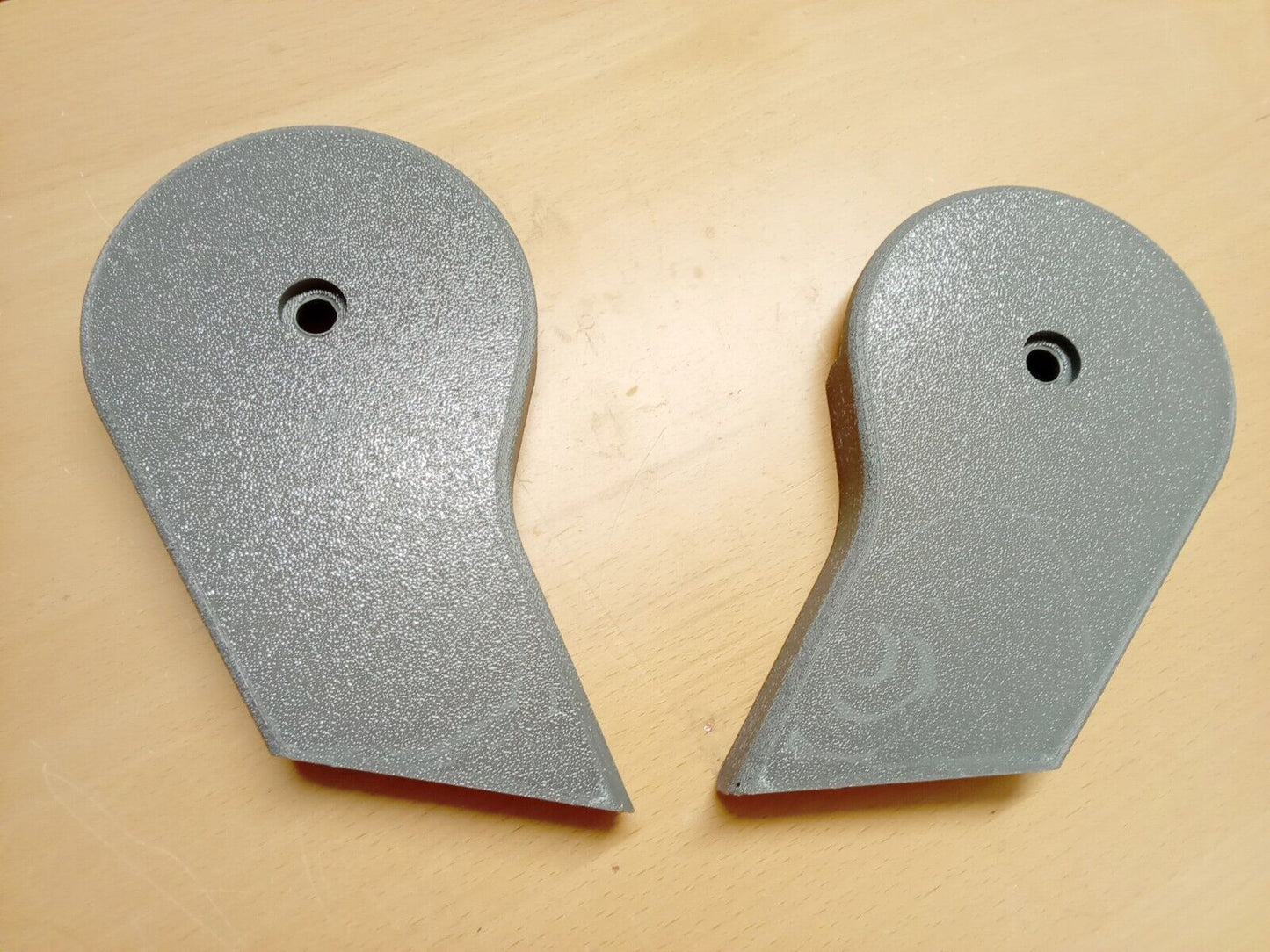A pair of light opal gray, textured plastic split seat hinge covers for 1992-1997 Ford F150, F250, and F350 OBS trucks. Each teardrop-shaped cover features a rounded top with a central mounting hole and an angled bottom edge.
