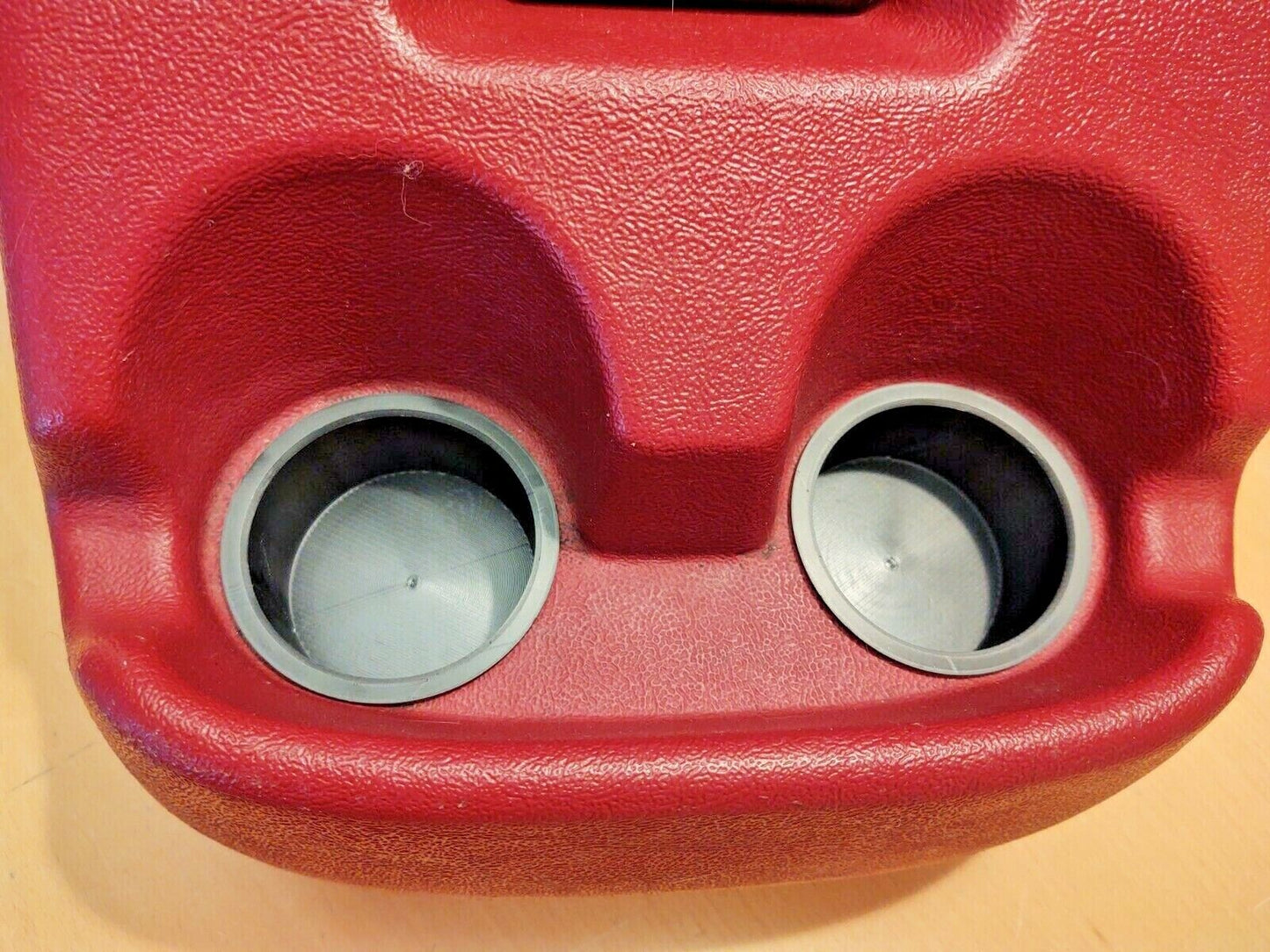 Two grey circular cup holder inserts installed in a textured red center console for 1992-1996 Ford F-150, F-250, F-350, and Bronco trucks.