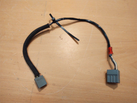 Original OEM Ford factory clock wiring harness for 1980-1986 F150, F250, F350, and Bronco, featuring black insulated wires with a protective black sleeve and grey rectangular plastic connectors at each end.